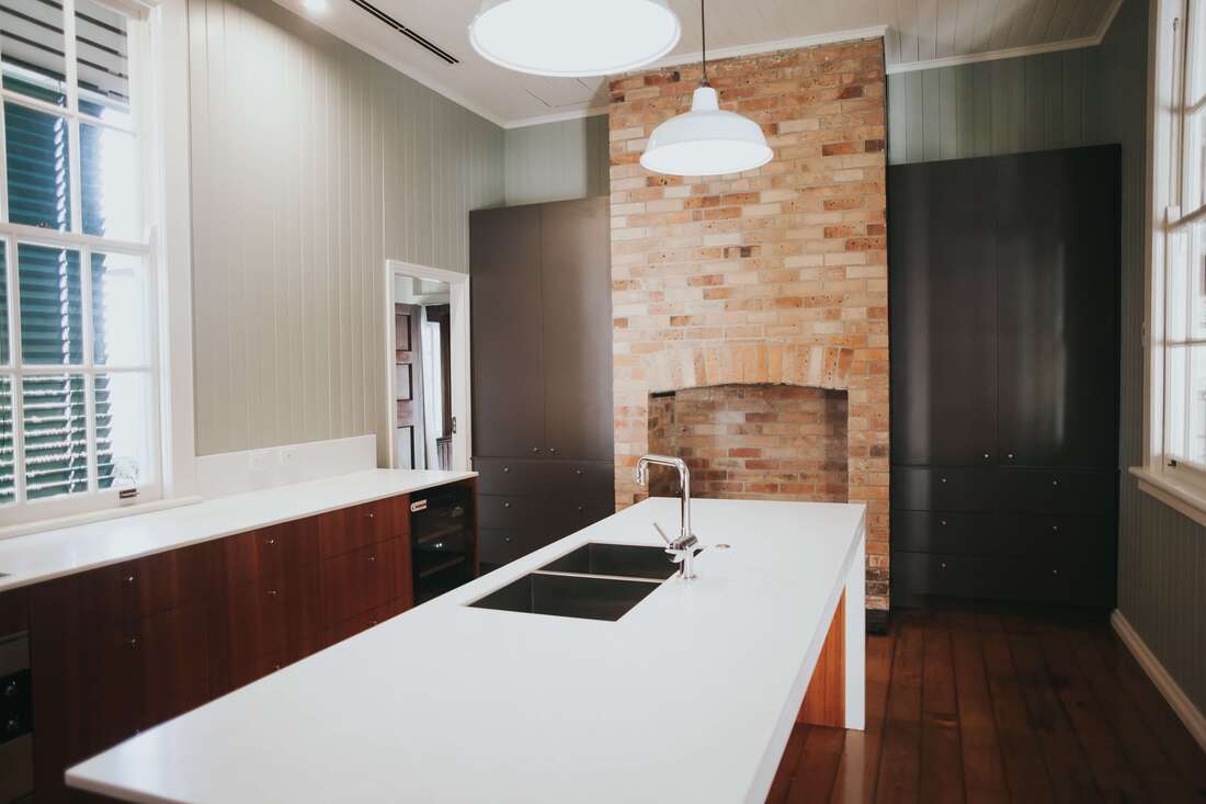 brick oven pizza stove with white quartz countertop with brown wood cabinets and finished wood tiled flooring with a steel foist